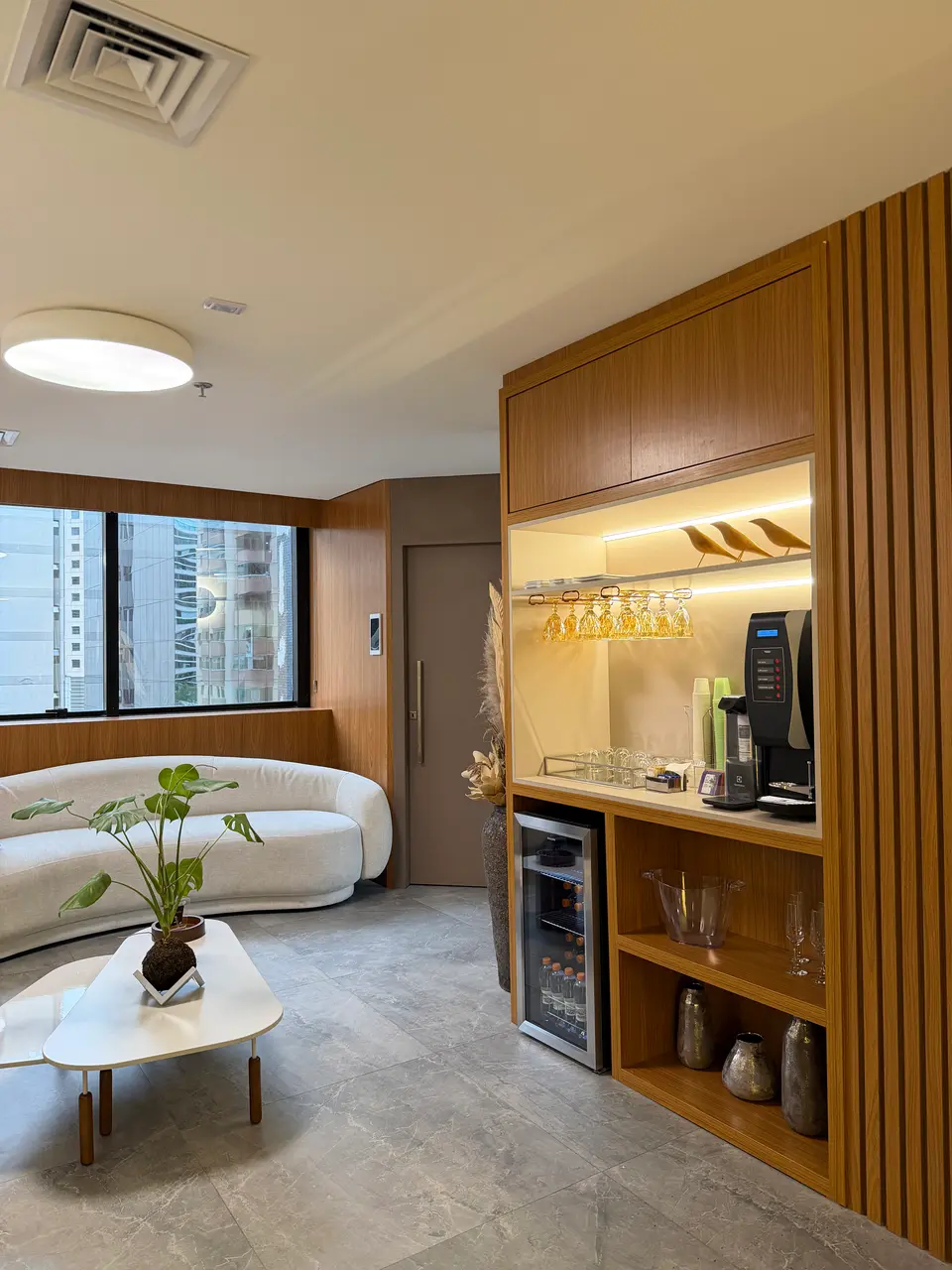 Sala de espera do consultório, com sofá claro, plantas e painel de madeira